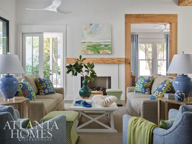 Living room with neutral sofas, patterned pillows, blue lamps, and a white coffee table.