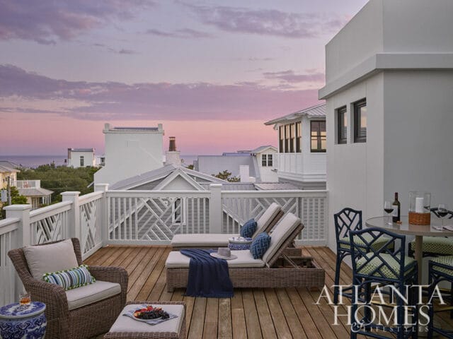 Rooftop deck with lounge chairs, dining table, and ocean view at sunset.