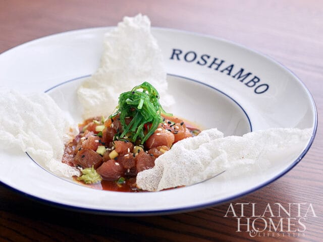 Tuna poke with seaweed salad and crispy wonton chips on a white plate with Roshambo text