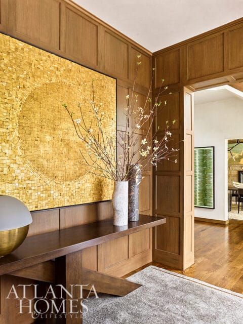 Wood paneled entryway with gold mosaic art and floral arrangement