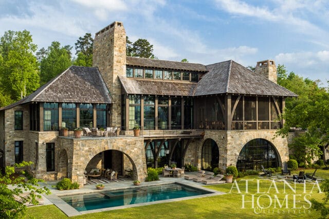 Stone mansion with wood accents, arched windows, screened porch, and swimming pool.