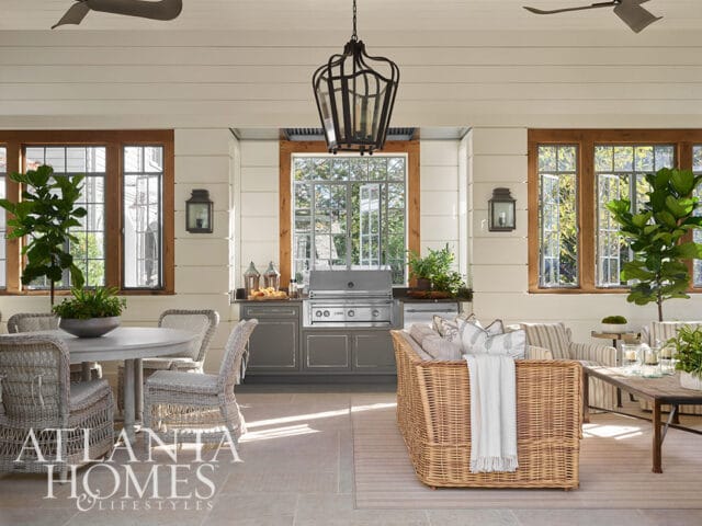 Covered patio with outdoor kitchen, dining table, and wicker seating.