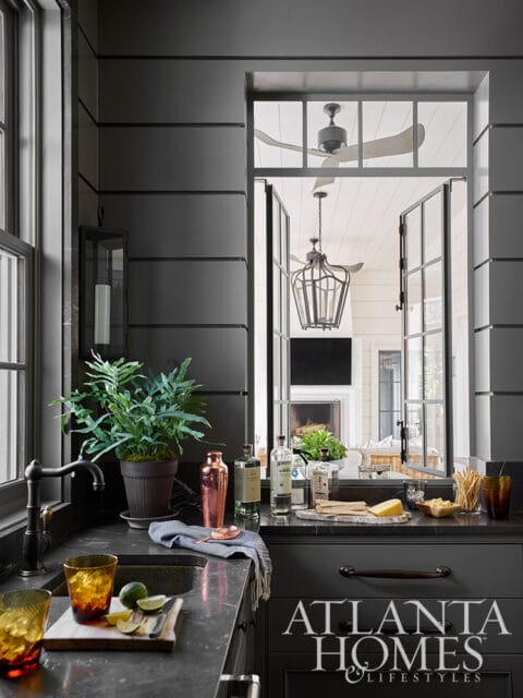 Dark gray kitchen with marble countertops, copper shaker, and bottles of liquor.