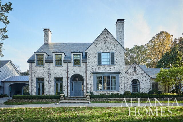 White brick house with gray roof, dormer windows, and blue shutters. Atlanta Homes & Lifestyles