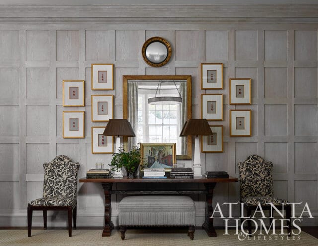 Entryway with paneled walls, console table, two chairs, and framed art.