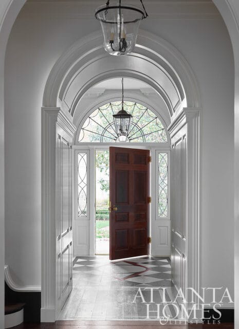 Entryway with arched ceiling, dark wood door, leaded glass sidelights, and patterned floor