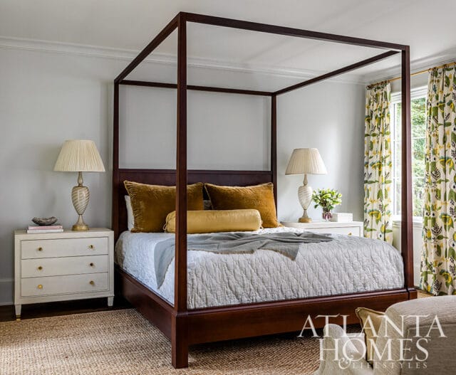 Bedroom with dark wood four-poster bed, white quilted comforter, gold pillows, and floral curtains.