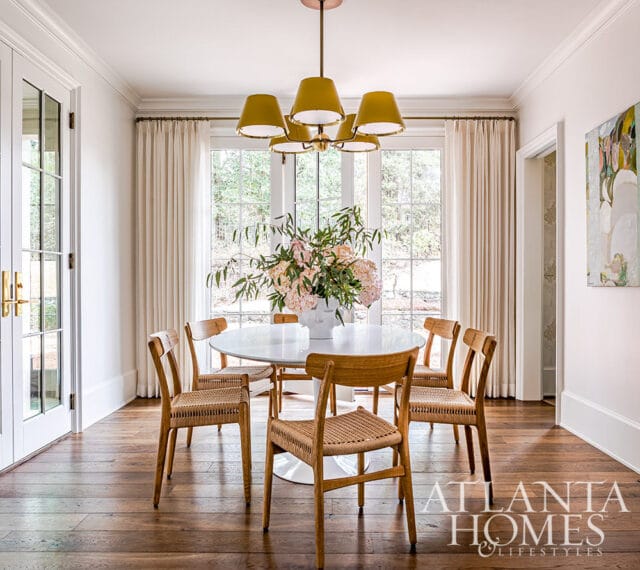 Dining room with white tulip table, woven chairs, and mustard chandelier.