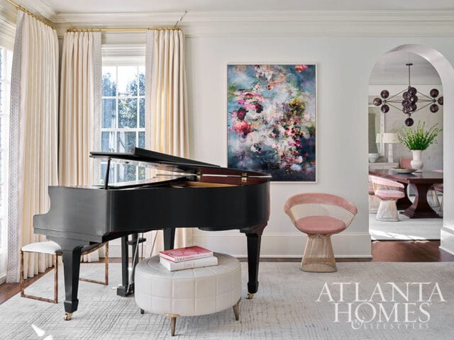 Grand piano in living room with abstract floral art and pink chair.