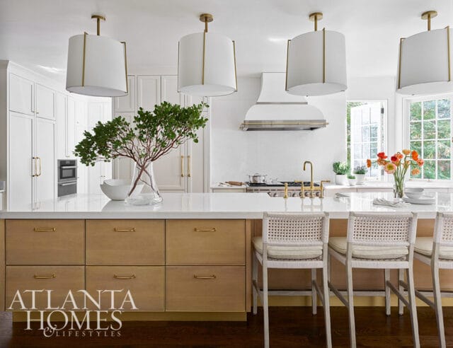 White kitchen with wood island, cane bar stools, and brass accents.