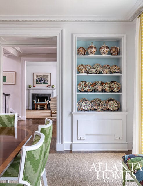 Built-in white shelving with blue backing displays decorative plates and vases.