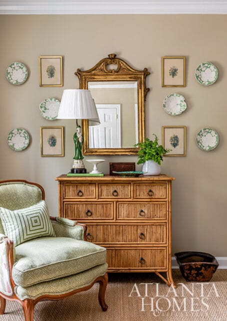 Green upholstered chair next to a bamboo dresser with a gold mirror above