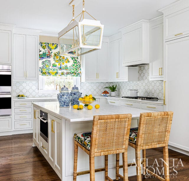 White kitchen island with marble countertop, rattan stools, and blue ginger jars.
