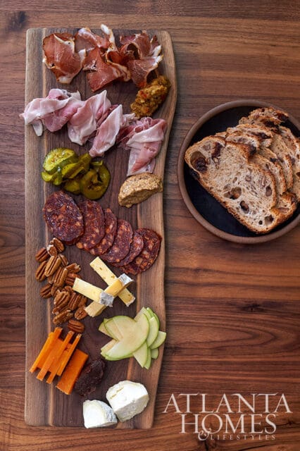 Charcuterie board with prosciutto, salami, cheese, pickles, nuts, and bread