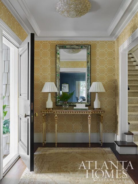 Entryway with yellow geometric wallpaper, console table, mirror, and patterned runner.