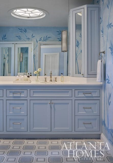 Blue bathroom vanity with white countertop, bamboo wallpaper, and octagonal floor tiles.