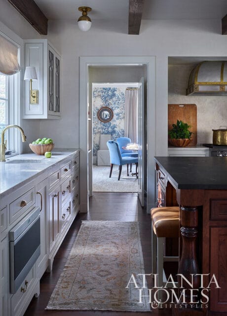White kitchen with marble countertops, light wood cabinets, and a doorway to a blue and white