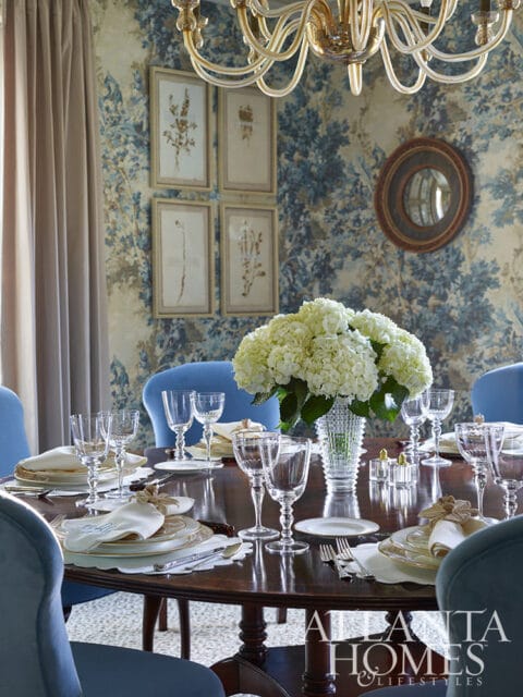 Dining room with blue floral wallpaper, a chandelier, and a table set for dinner.