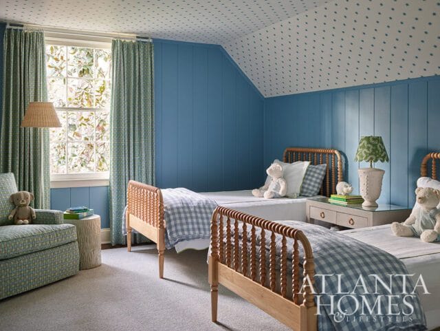 Blue paneled walls and ceiling with star pattern, two twin beds with gingham bedding, armchair, and