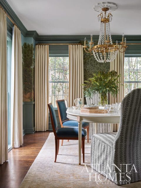 Dining room with teal walls, cream curtains, and a crystal chandelier.