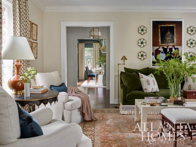 Living room with white chairs, green sofa, patterned rug, and artwork.