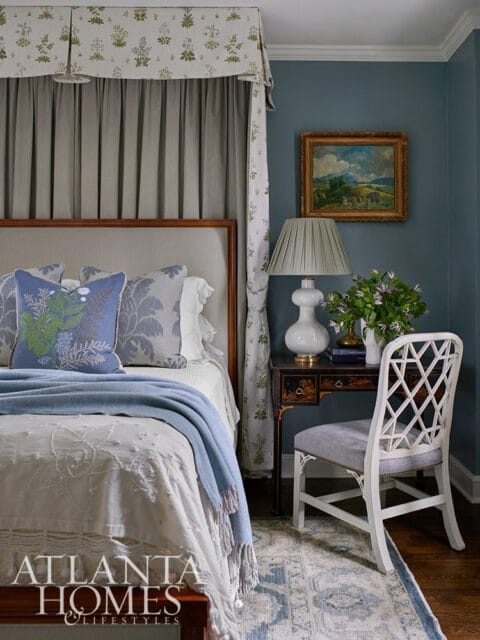 Bedroom with blue walls, upholstered bed, floral canopy, and lattice-back chair.