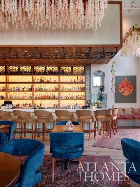 Bar with backlit shelves of liquor bottles, marble counter, and brown bar stools.