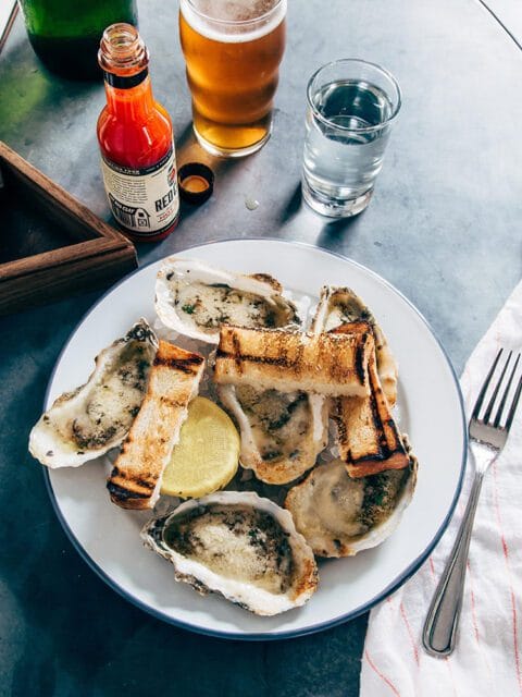 Plate of baked oysters with grilled bread and lemon wedge