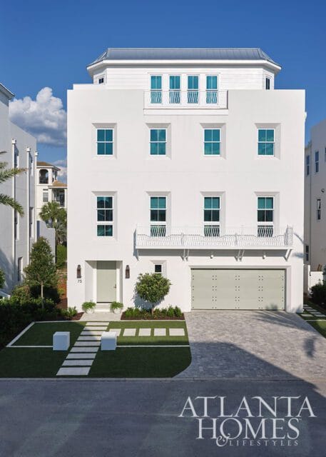 White modern house with teal windows, a light green door, and a grey garage door.