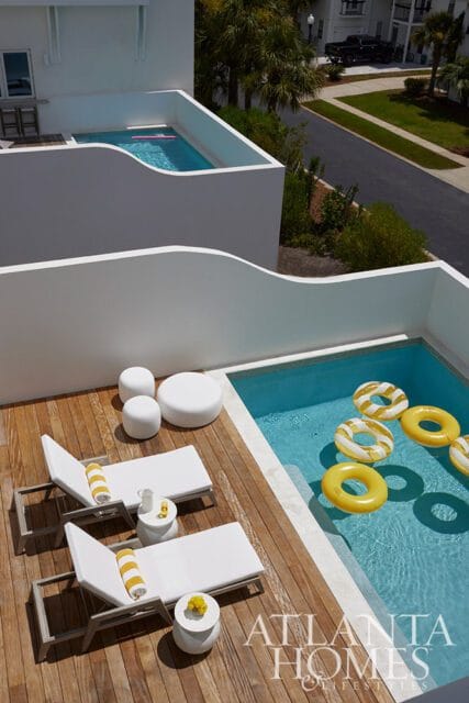 Deck with lounge chairs and a pool with yellow inflatable rings.