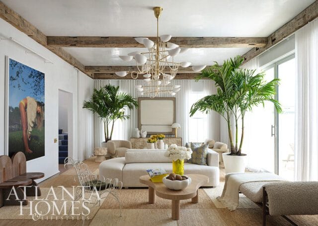 Living room with white sectional sofa, wood coffee table, and large palm plants.