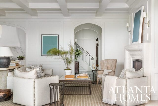 Living room with white paneled walls, coffered ceiling, fireplace, and staircase.