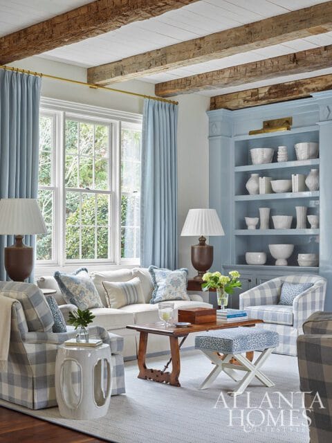 Living room with blue and white plaid chairs, sofa, light blue curtains, and built-in shelves.