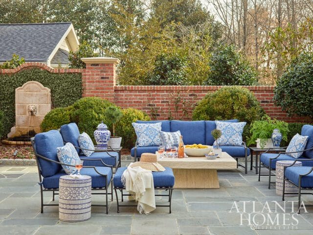 Patio with blue outdoor furniture, stone table, and fountain.