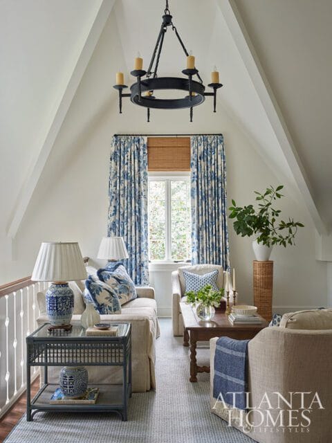 Living room with blue floral curtains, neutral furniture, and a dark chandelier.