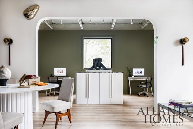 Modern office with olive green walls, white cabinets, and desks with computers.