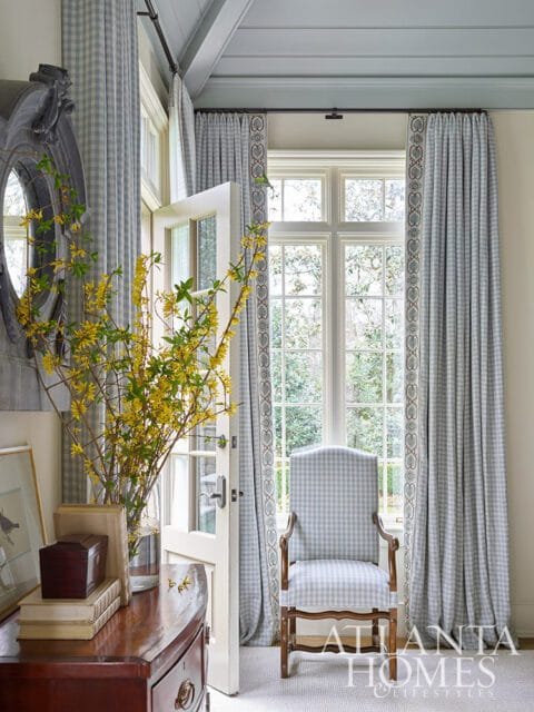 Blue gingham armchair in front of a window with matching curtains.