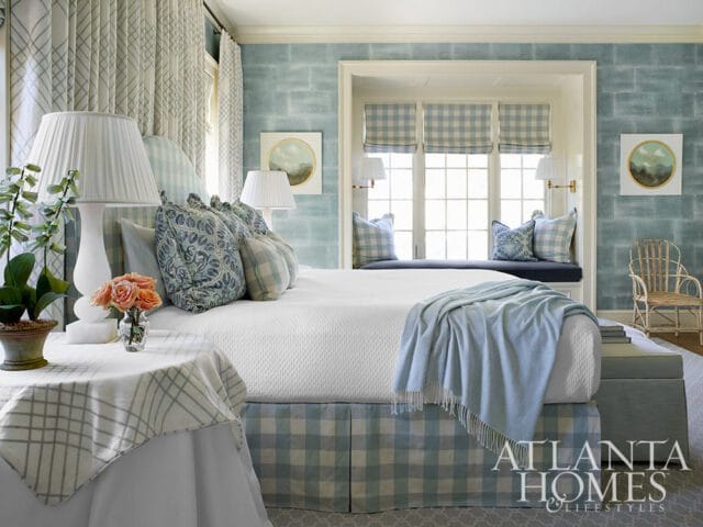Bedroom with blue and white buffalo check accents, textured blue wallpaper, and a window seat.