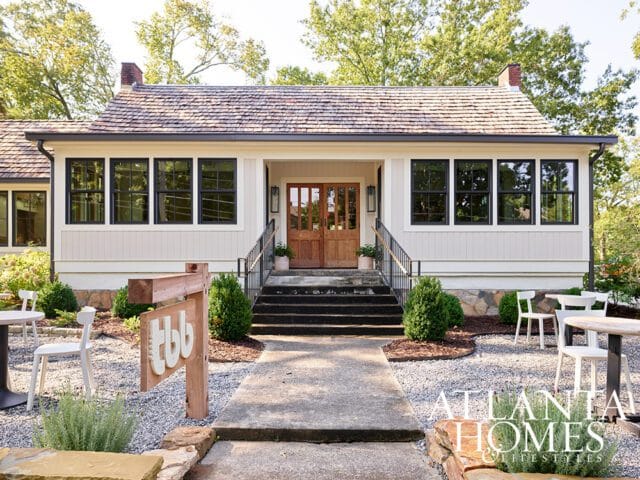 Cream siding house with wood shake roof, double front doors, and stone foundation.