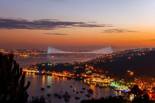 Bosphorus Bridge at night with city lights reflecting on the water