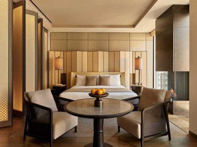 Deluxe suite bedroom with upholstered headboard, fireplace, and seating area.