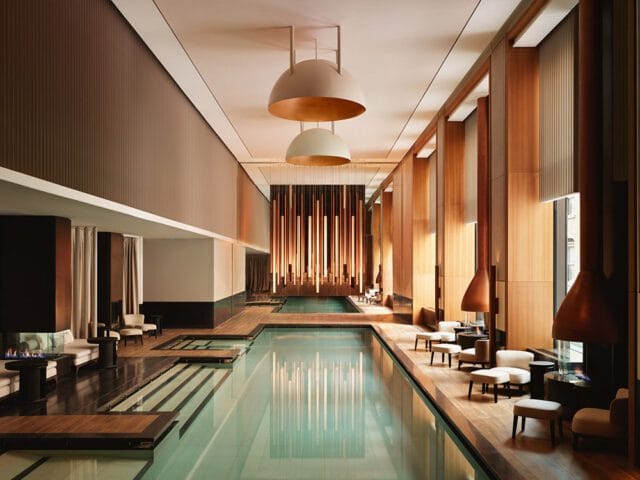 Indoor pool with wood paneling, modern fireplaces, and lounge seating.