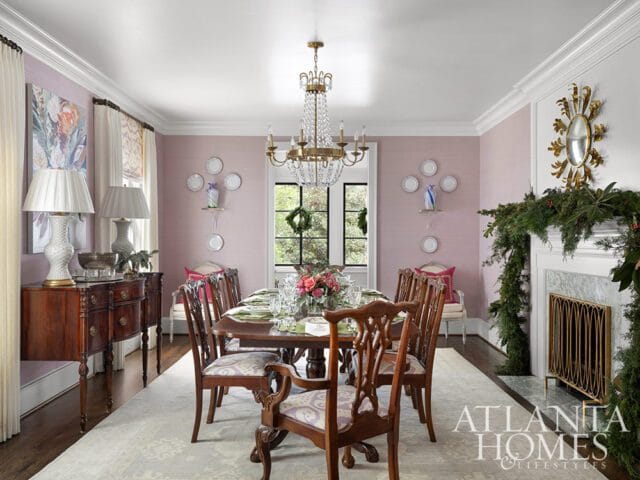 Dining room with pink grasscloth walls, mahogany table, and fireplace decorated for Christmas.