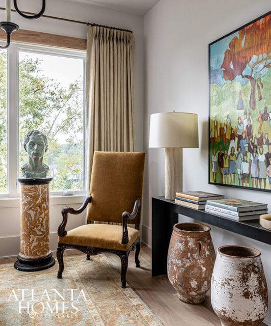 Velvet armchair next to bust on pedestal and abstract painting