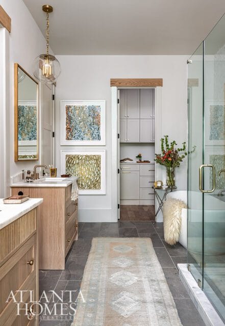Bathroom with wood vanity, marble countertop, glass shower, and abstract art.