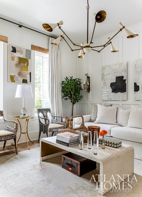 Living room with white sofa, abstract art, modern chandelier, and a waterfall coffee table.