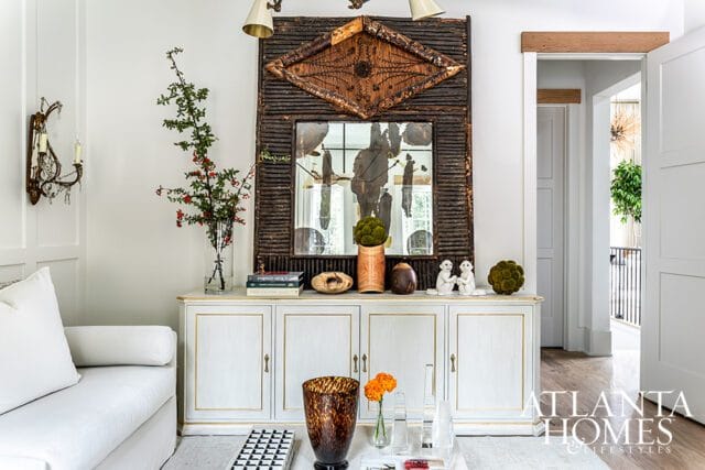 White cabinet with gold trim, topped with mirror and decorative objects.