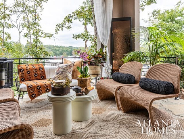 Covered patio with wicker chairs, sofa with patterned throw, and potted plants.