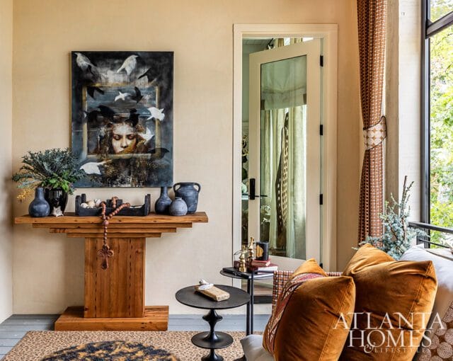 Living room with abstract art, wooden console table, velvet pillows, and Atlanta Homes & Lifestyles