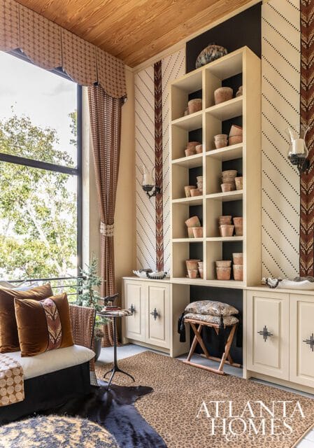 Cream built-in shelves and cabinets with terracotta pots, patterned wallpaper, and large window.